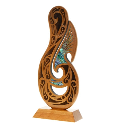 Wooden fish hook award with intricate designs, featuring inlayed Pāua shell